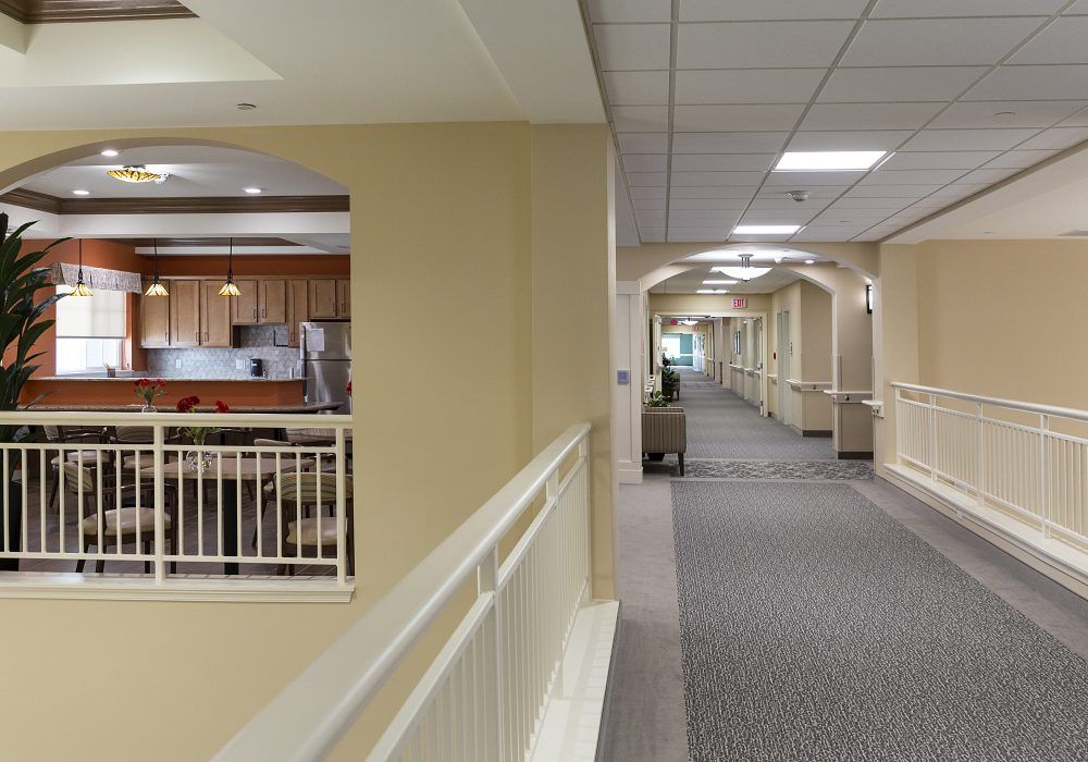 A well-lit corridor with a view of an adjacent open kitchen area.