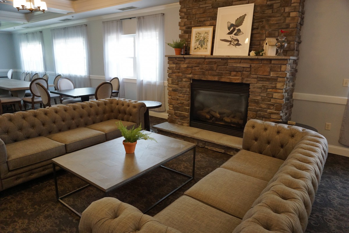A cozy living room with a brick fireplace, tufted sofas, and a central coffee table adorned with a small plant.