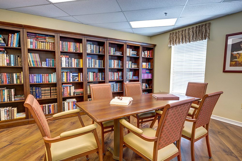 A quiet library space with bookshelves, a table, and chairs for reading or meetings.