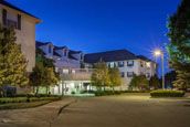A residential building illuminated at night with surrounding trees and streetlights.
