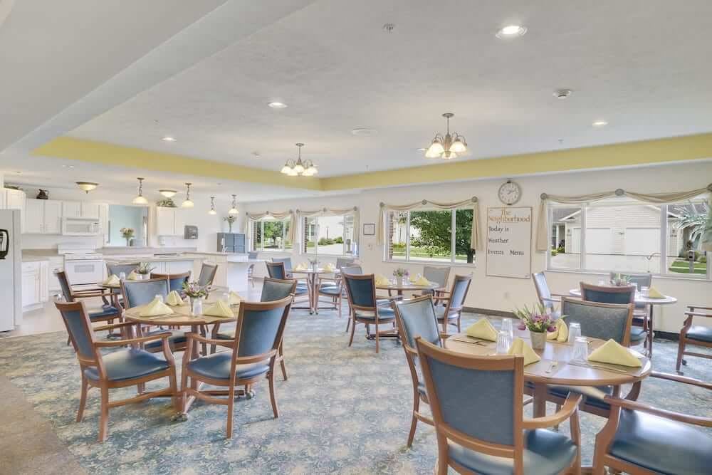 A spacious and well-lit dining room featuring neatly arranged tables and chairs, with large windows allowing natural light to fill the space.