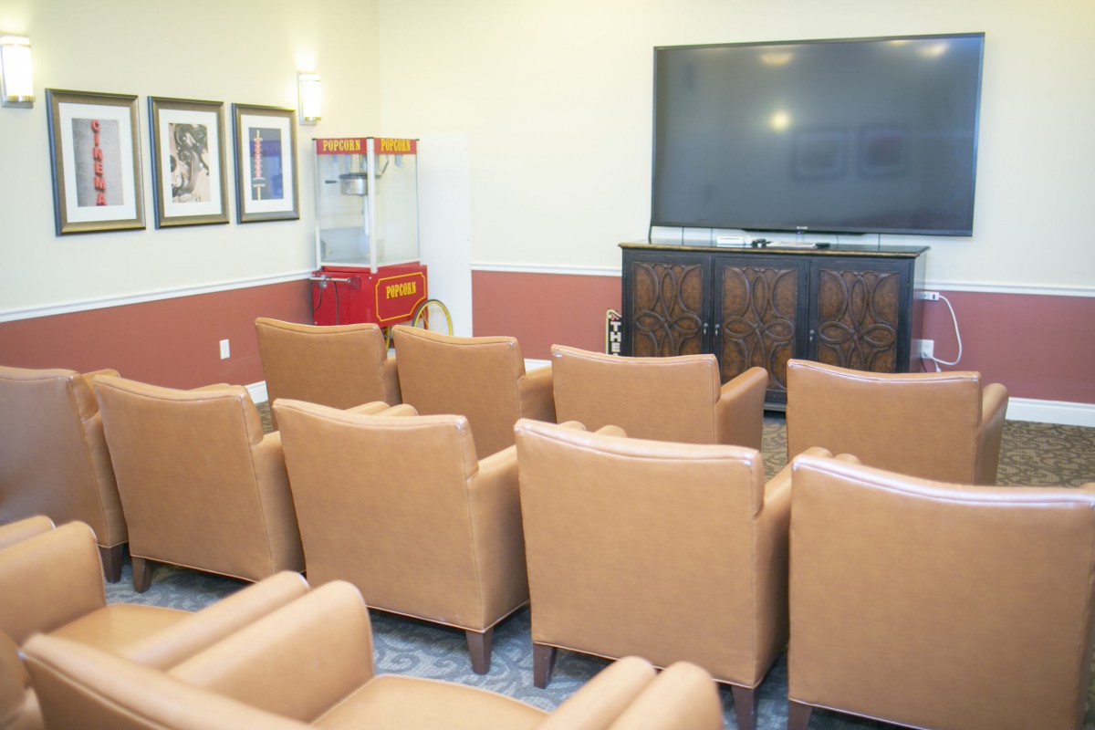 A cozy home theater setup with comfortable seating and a large screen, complete with a popcorn machine for an authentic cinema experience.