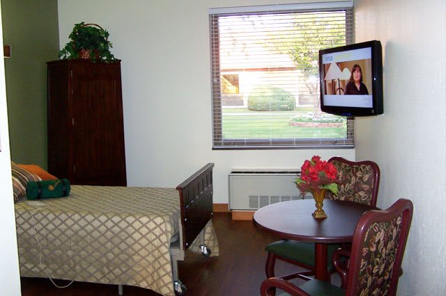 A cozy room featuring a TV, table with flowers, and a window.