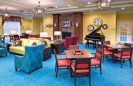 A cozy lounge area with colorful seating, a piano, and decorative clocks.