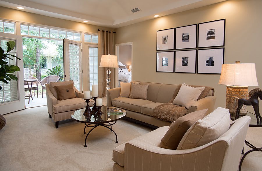 A cozy living room with beige furniture, elegant decor, and framed artwork on the wall.