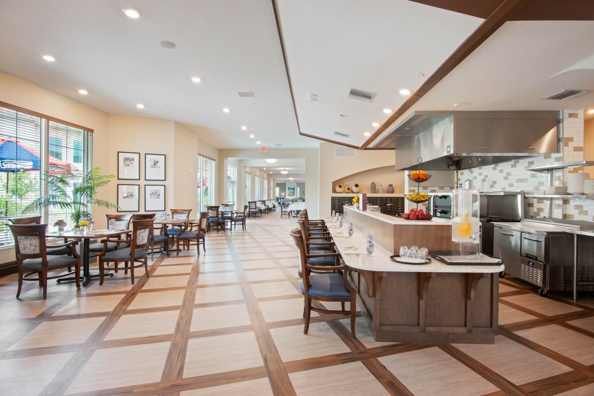 A modern restaurant interior with a spacious dining area, featuring neatly arranged tables and chairs.