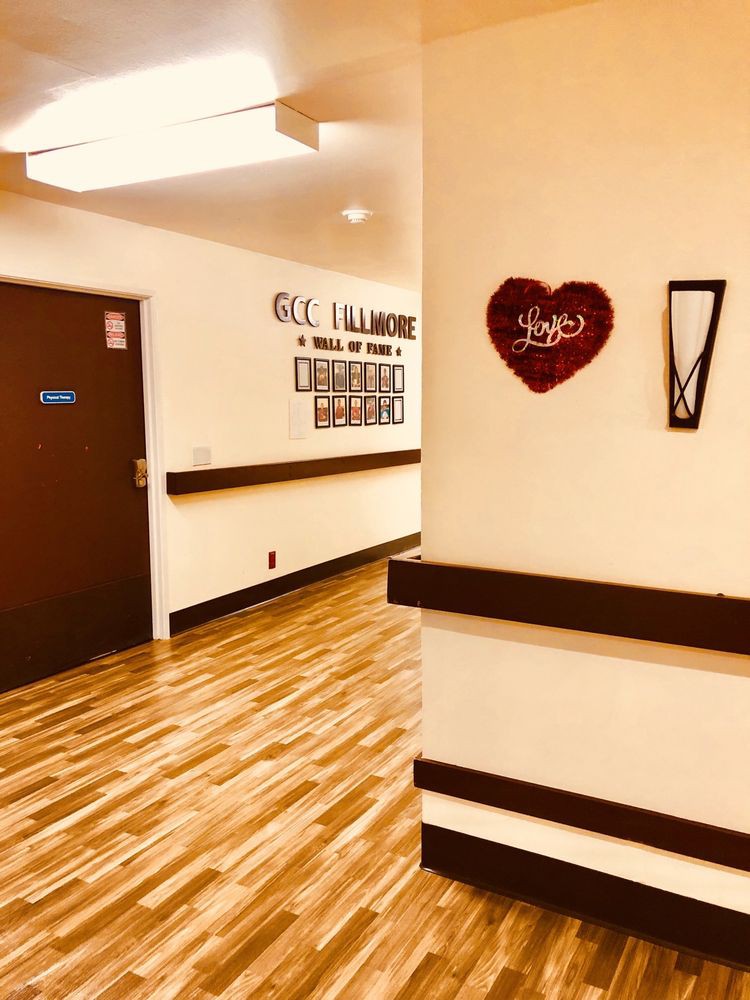 A hospital hallway with wooden flooring and heart-shaped wall decor.