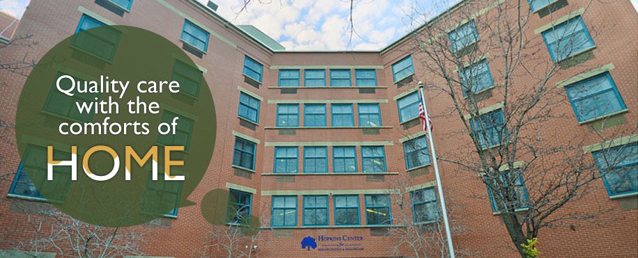 A brick building with multiple windows and trees in the foreground.