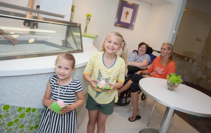 Two children enjoy ice cream while their family relaxes in the background.