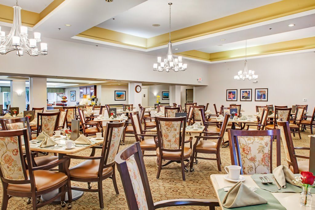 An elegant dining room featuring numerous tables and chairs adorned with chandeliers.