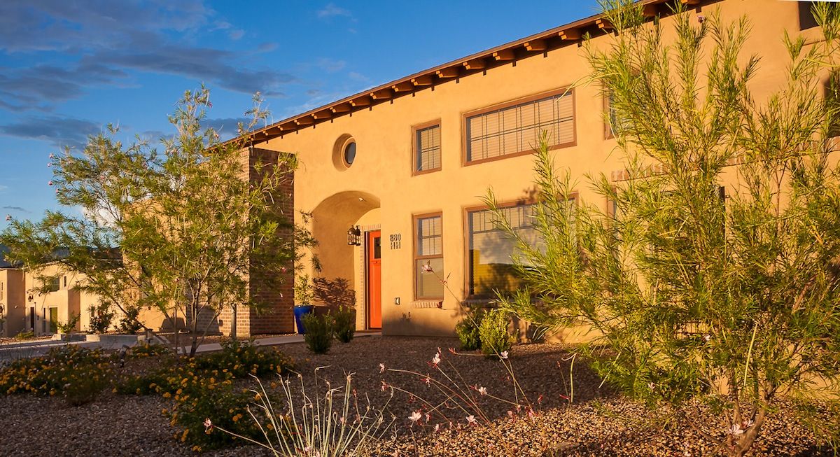 A beautifully lit house with desert landscaping and an arched doorway.