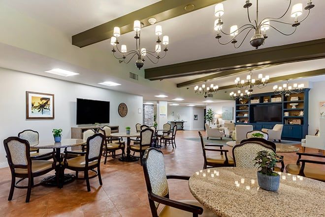 A beautifully designed dining area with chandeliers, wooden beams, and neatly arranged tables and chairs.