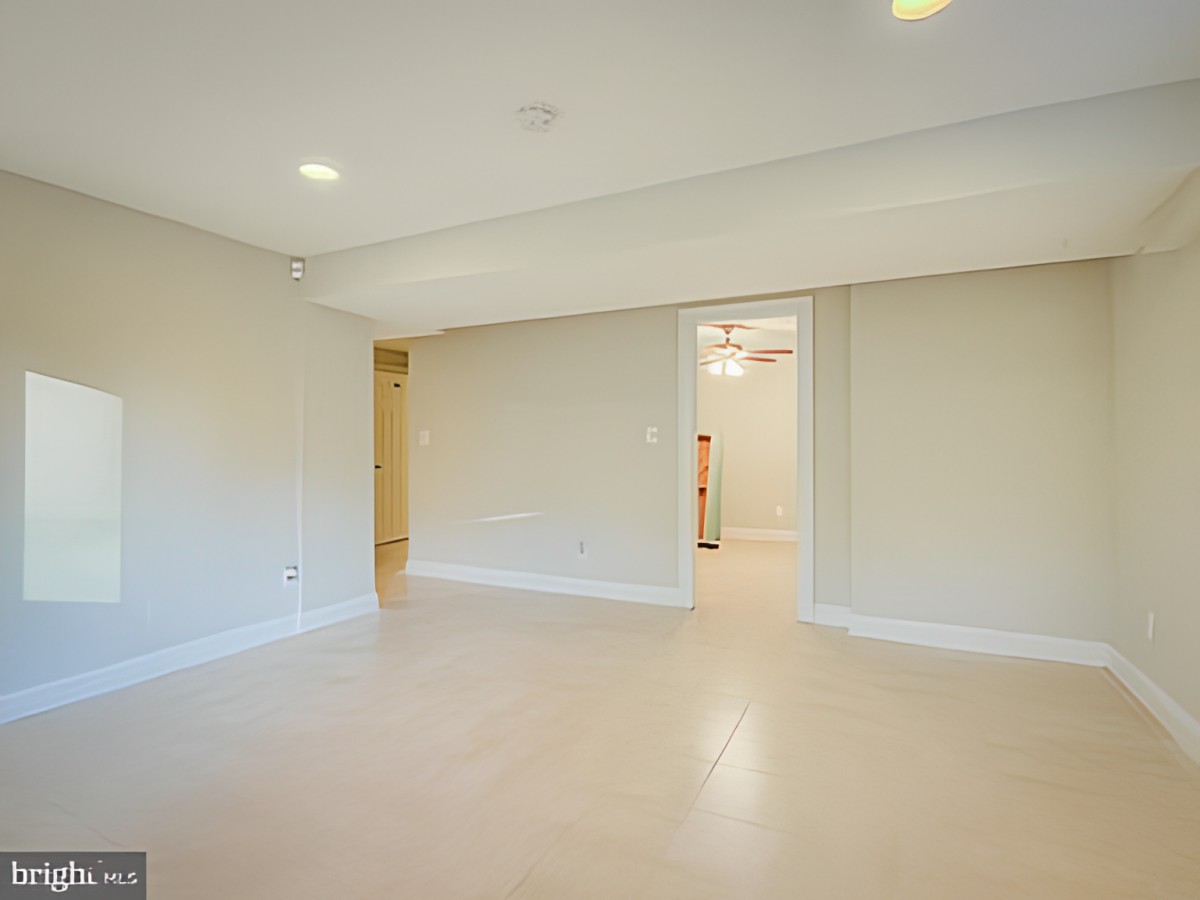 An empty room with wooden flooring, neutral-colored walls, and recessed lighting.