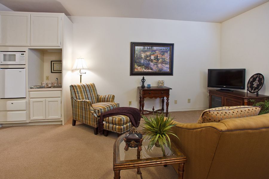 A cozy living room with comfortable seating, a table lamp, and a television.