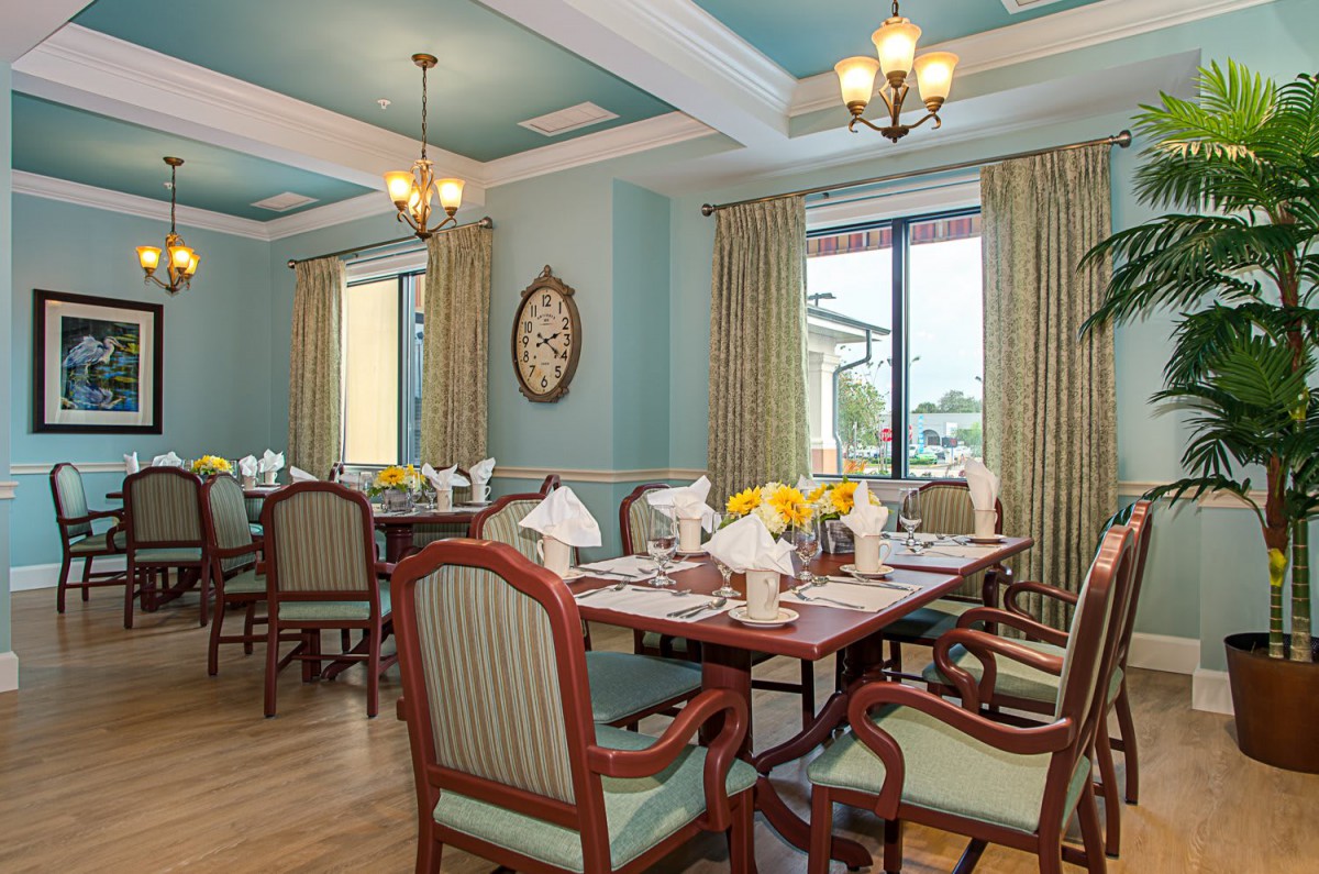 An elegant dining room with neatly arranged tables and chairs, featuring chandeliers and tasteful decor.