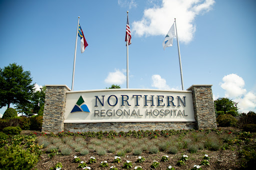 Entrance sign of Northern Regional Hospital featuring flags and landscaping.