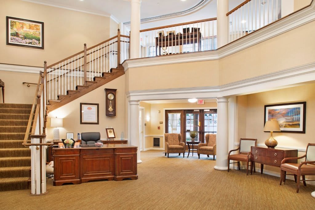A spacious and elegantly designed lobby with a reception desk, staircase, and comfortable seating area.