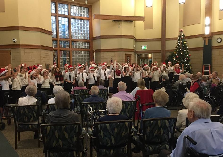 A choir performing a Christmas concert for a senior audience in a decorated indoor venue.