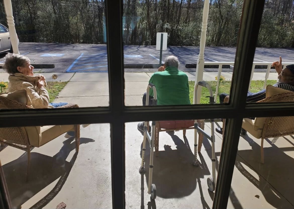 People sitting in wheelchairs enjoying the outdoor sunlight.