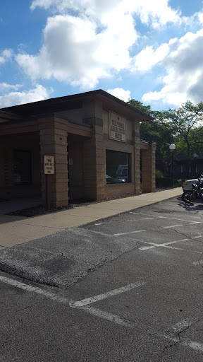 A corner view of a building with prominent architectural features and a parking area.