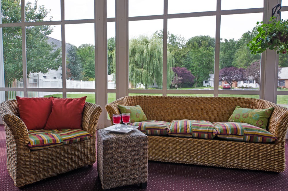 A cozy sunroom featuring wicker furniture and a scenic outdoor view.