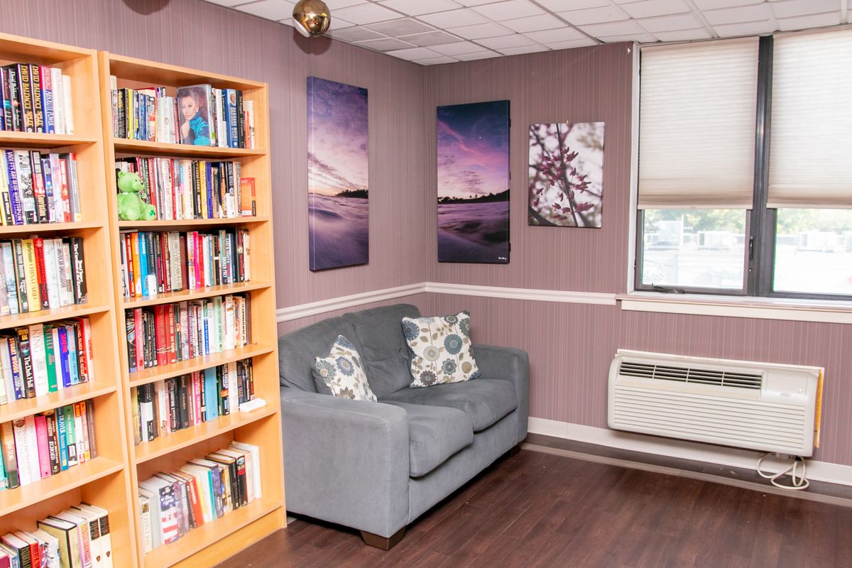 A cozy reading corner with a bookshelf, sofa, and wall art.