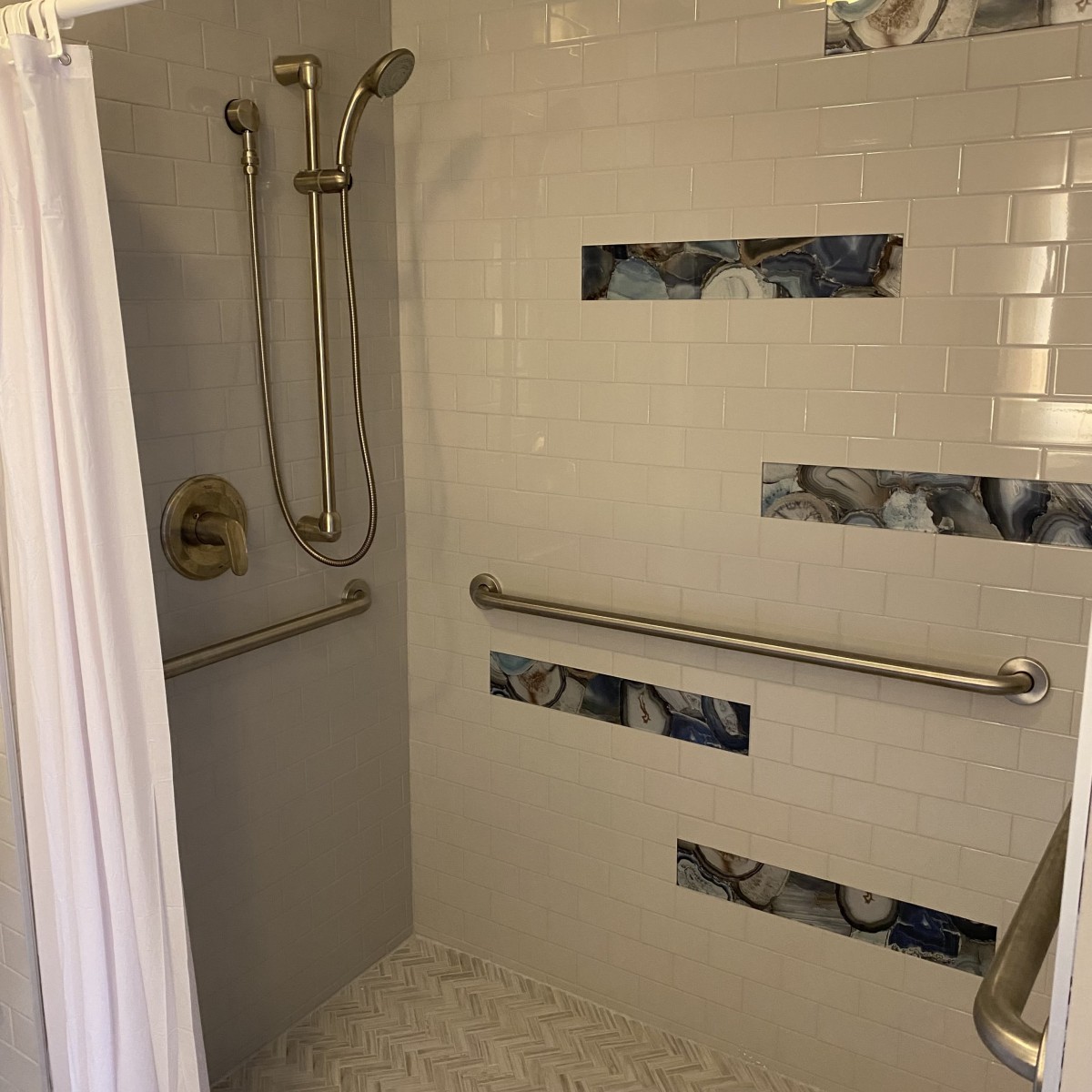 A modern shower with decorative tiles and safety grab bars.