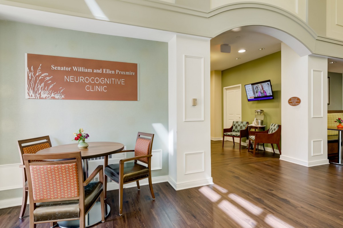 A waiting area in a healthcare clinic with chairs, a table, and a television.