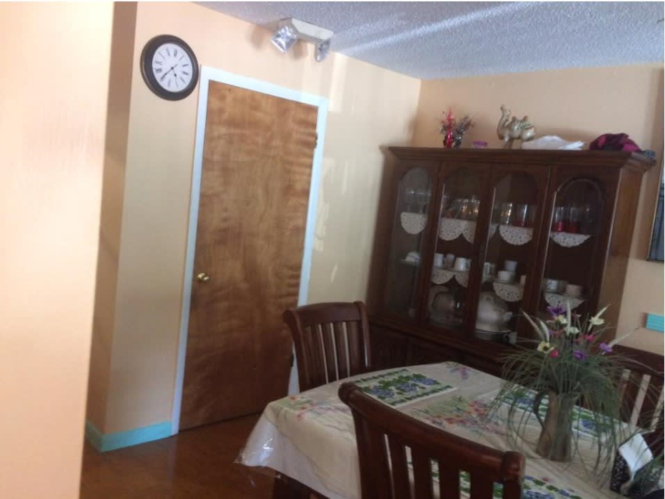 A cozy dining room with a wooden table, chairs, and a cabinet filled with dishes.