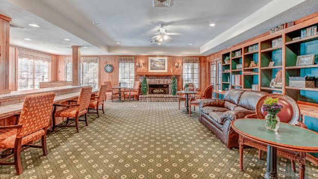 A cozy lounge area with a fireplace, comfortable seating, and bookshelves.