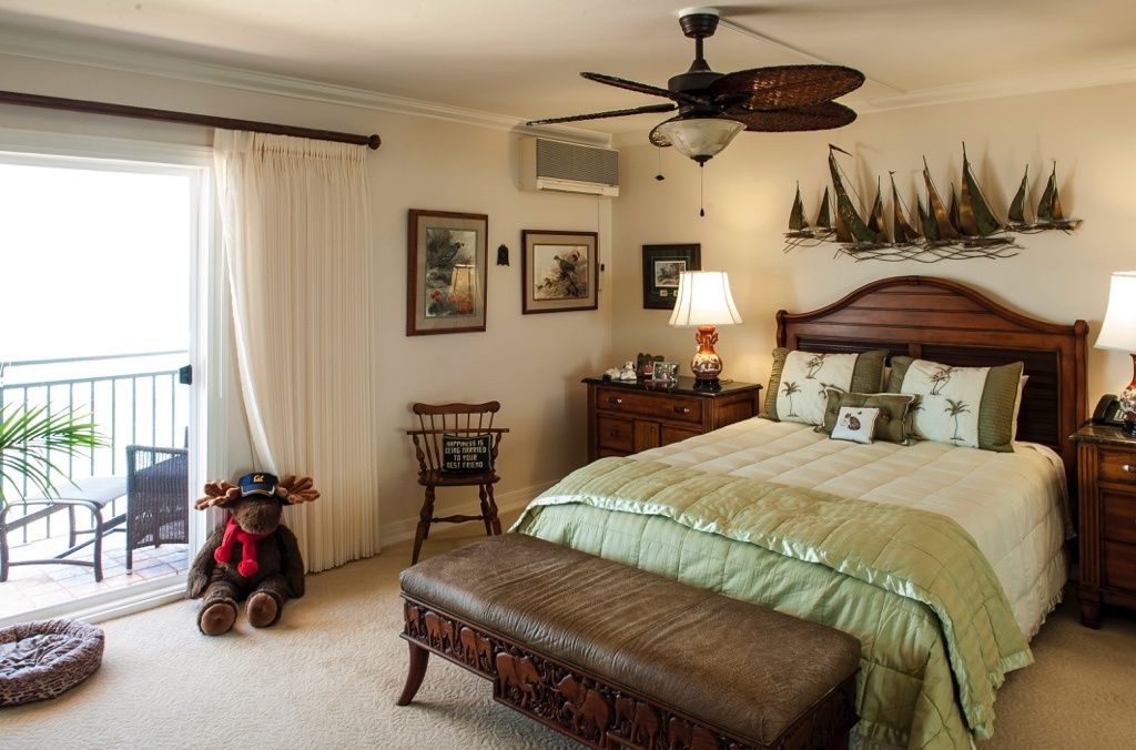 A cozy bedroom with elegant decor, featuring a large bed, ceiling fan, and soft lighting.