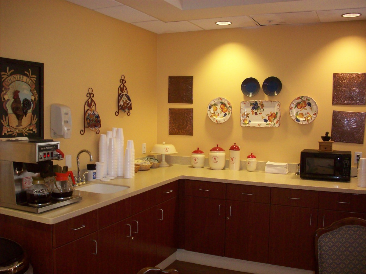 A cozy break room with a kitchenette, featuring a coffee station and decorative wall plates.