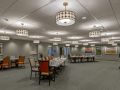 A spacious conference room with arranged tables and chairs under modern lighting.
