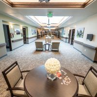 A spacious hallway with a seating area, featuring a round table with flowers and chairs.