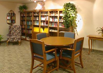 A cozy reading area with a round table, chairs, and bookshelves filled with books.