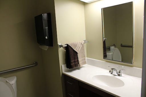 A clean and well-lit bathroom featuring a sink, mirror, and neatly hung towels.