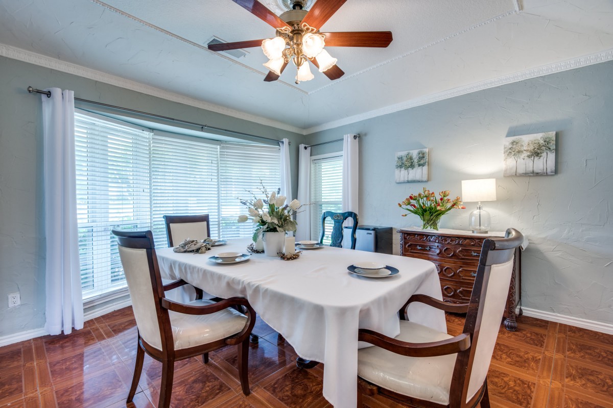 Elegant dining room with a table set for four, featuring flowers and natural light.