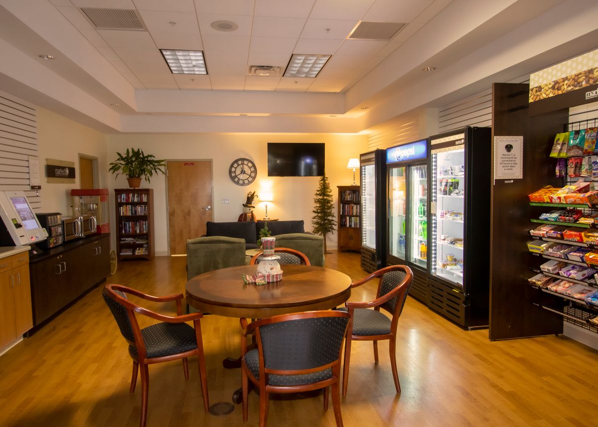 A cozy lounge area with a round table and chairs, surrounded by refrigerators and a television.