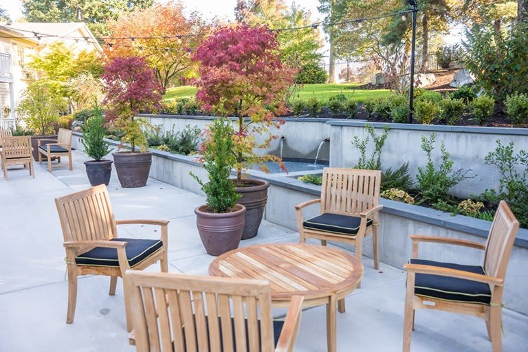 A beautifully arranged outdoor patio with wooden furniture and potted plants in an autumn setting.