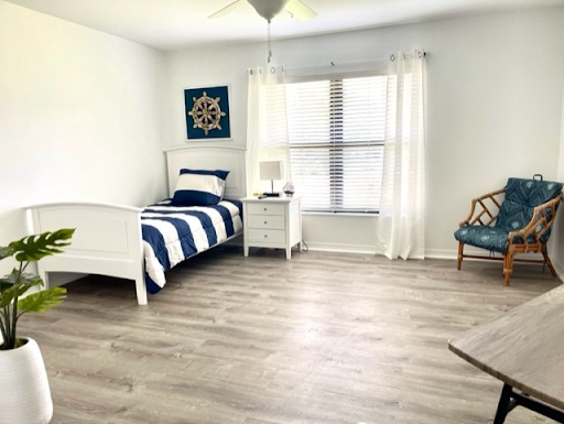 A bright and modern bedroom featuring a blue and white color scheme, natural light filtering through the windows, and minimalist decor.