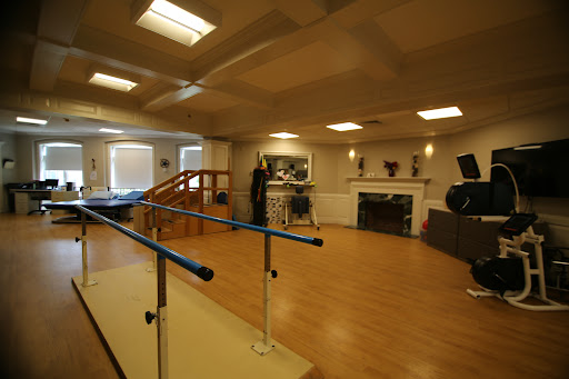 A spacious dance studio featuring a barre for exercise and rehabilitation.