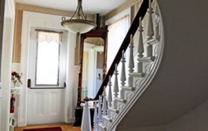 A well-lit hallway with a spiral staircase and chandelier.