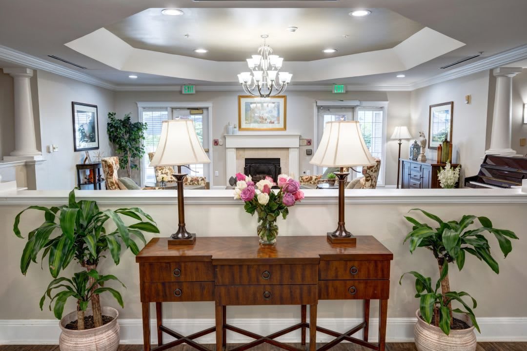 A well-decorated lobby interior with a wooden table, floral arrangement, and elegant lamps.