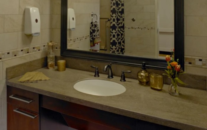 A well-organized bathroom countertop with a sink, mirror, and decorative soap dispensers.