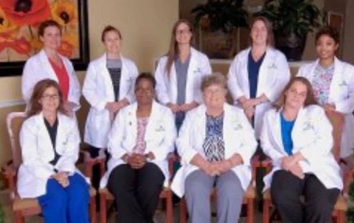 A group of medical professionals posing indoors, wearing white coats.