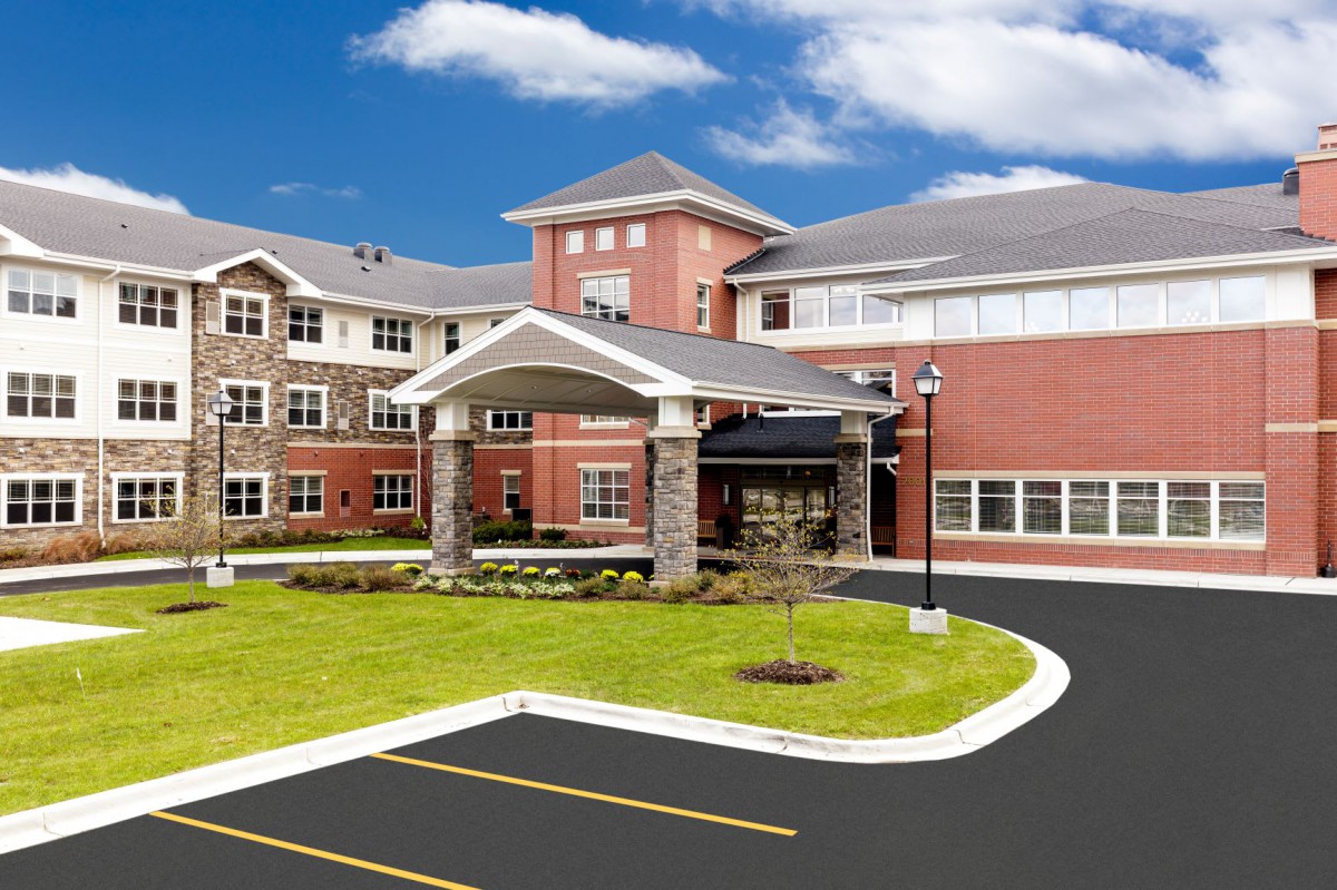 A modern residential building with a landscaped lawn and driveway.