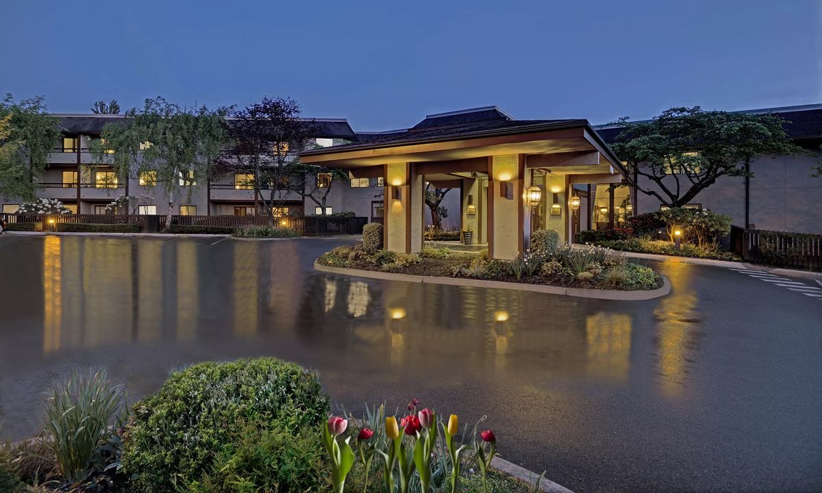 Elegant building entrance illuminated at night with landscaped gardens.