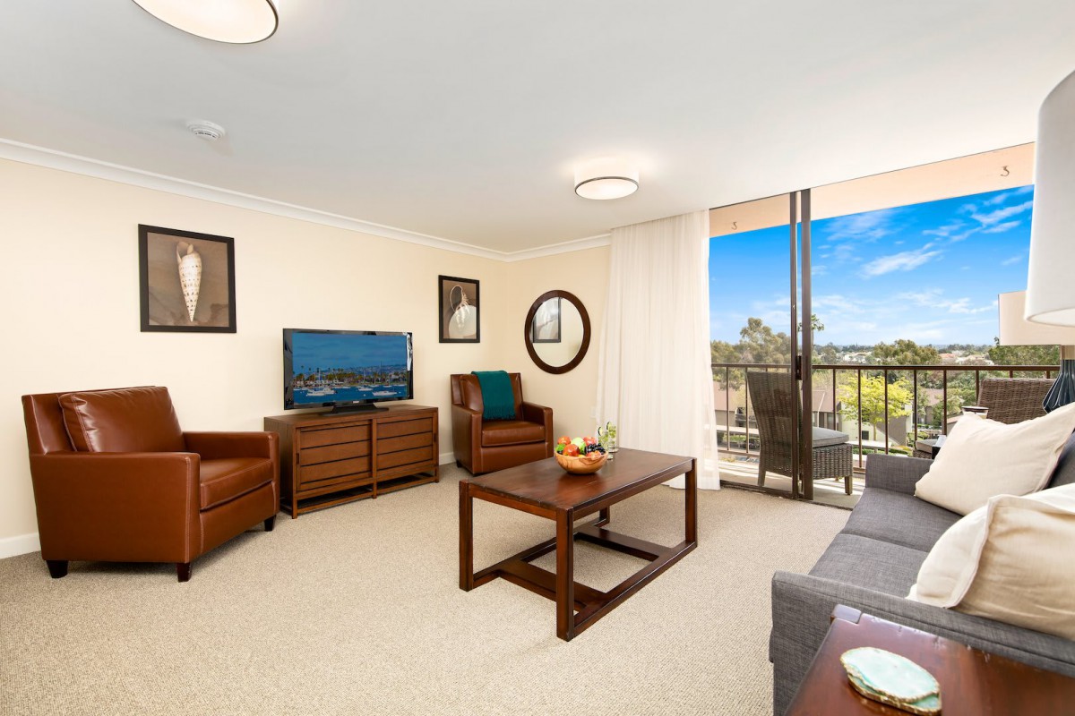 A modern living room with comfortable seating, a television, and a view from the balcony.