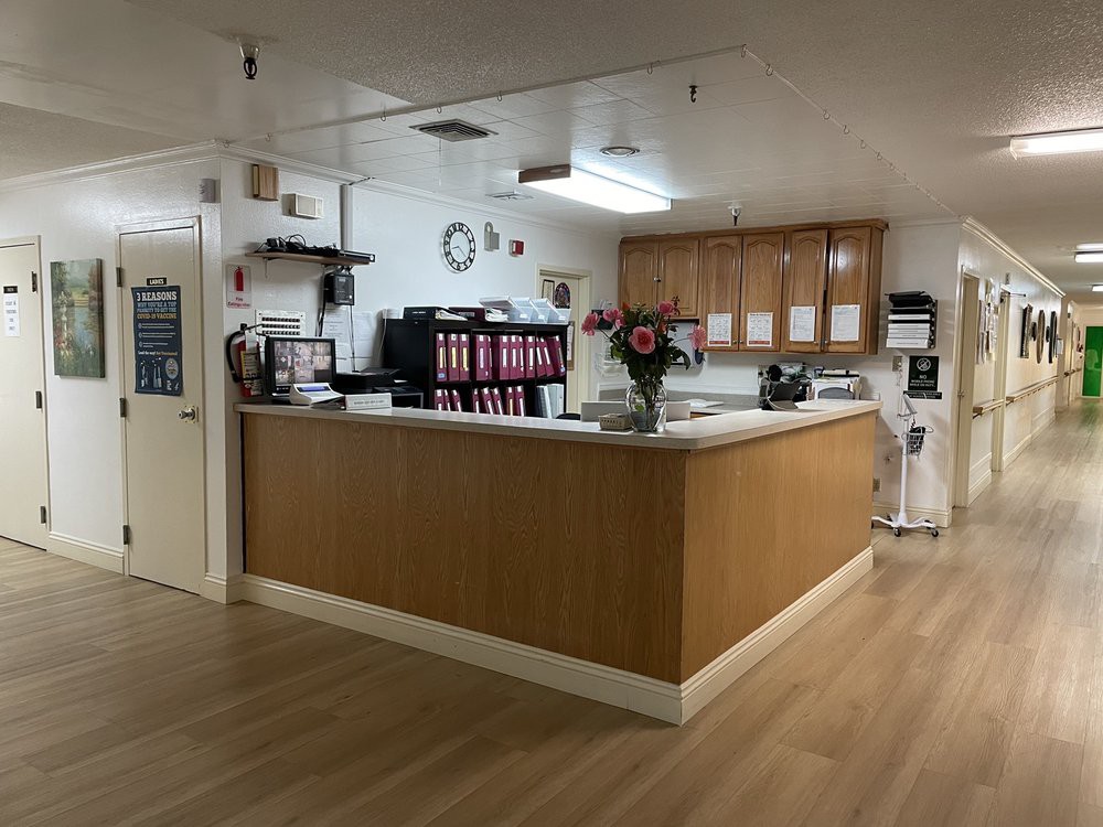 A clean and organized reception area with a wooden desk, office supplies, and decorative flowers.