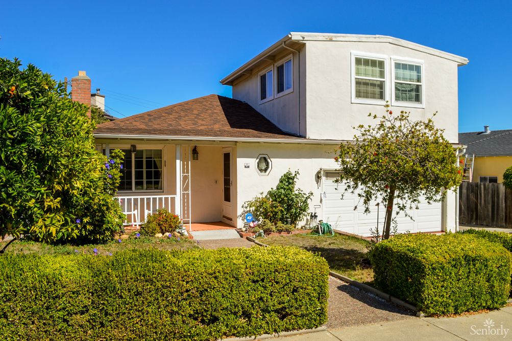 A suburban house with well-maintained landscaping and a clear blue sky.